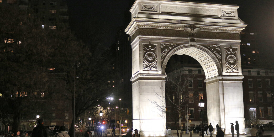 a large stone arch with lights at night
