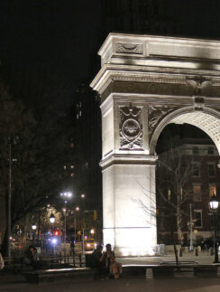 a large stone arch with lights at night