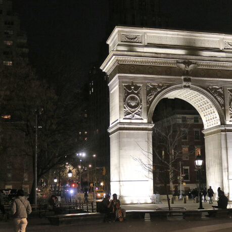 a large stone arch with lights at night