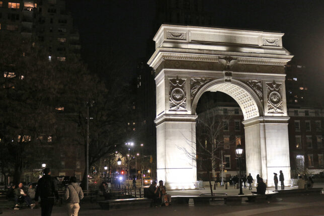 a large stone arch with lights at night