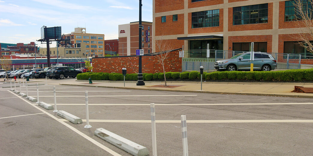 a street with white poles and cars parked on the side