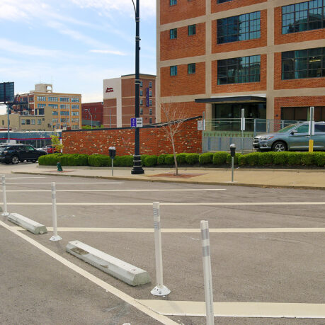 a street with white poles and cars parked on the side