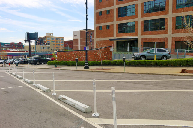 a street with white poles and cars parked on the side