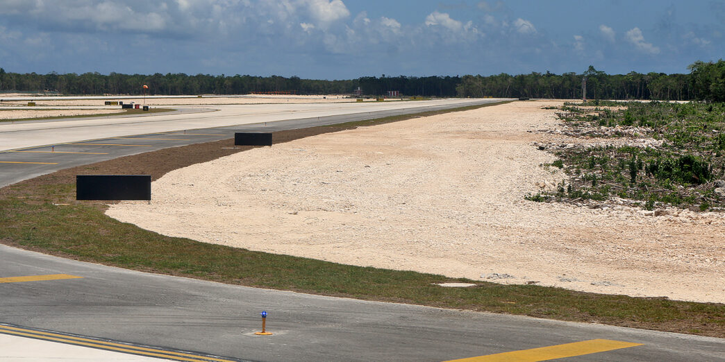 a runway with a road and trees