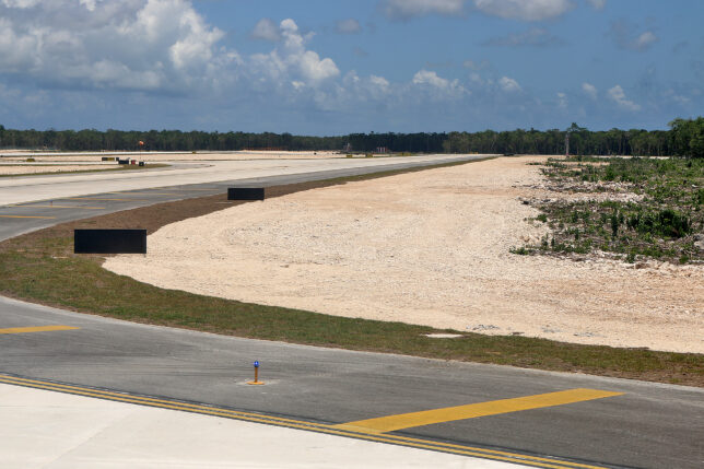 a runway with a road and trees