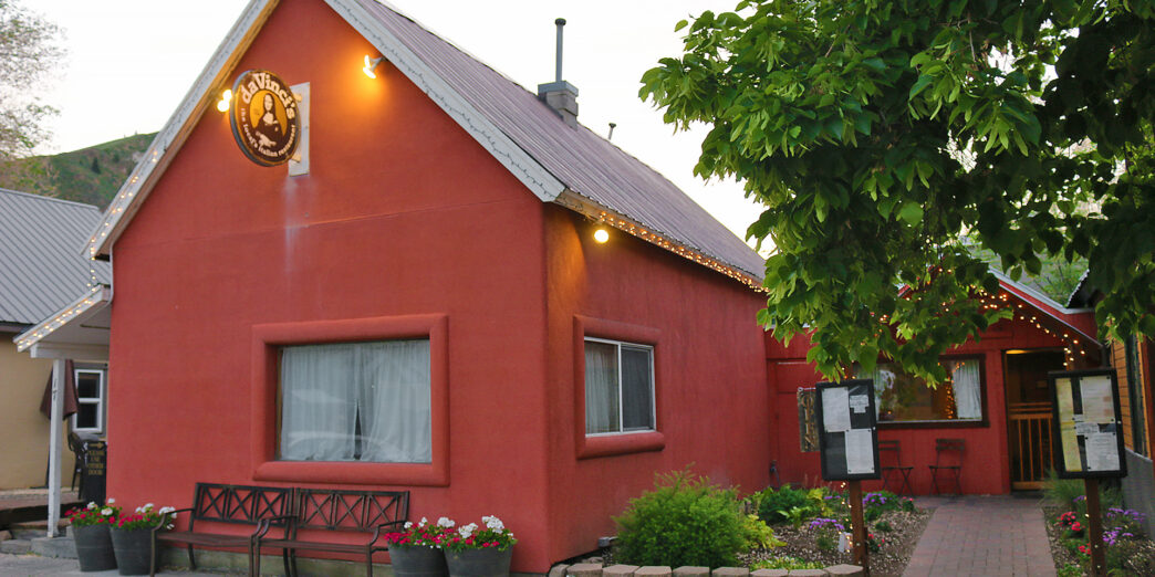 a red building with a sign and a tree