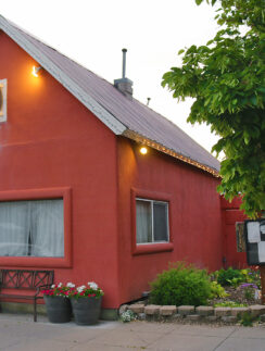 a red building with a sign and a tree