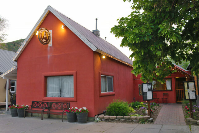 a red building with a sign and a tree