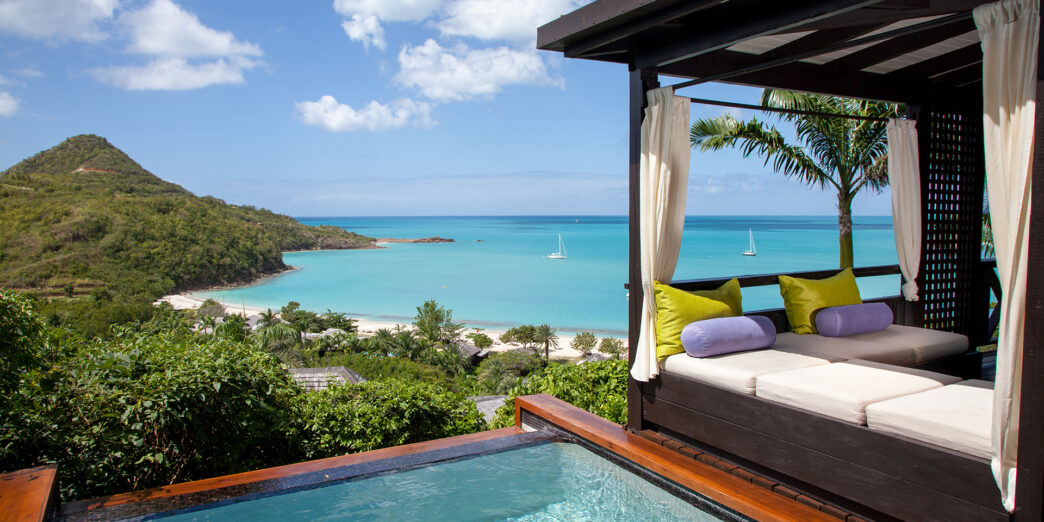 a pool with a bed and a beach in the background