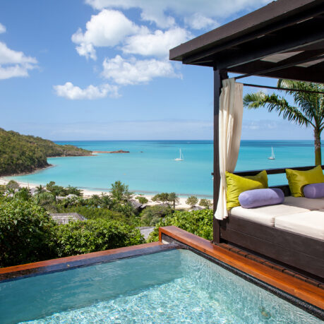 a pool with a bed and a beach in the background