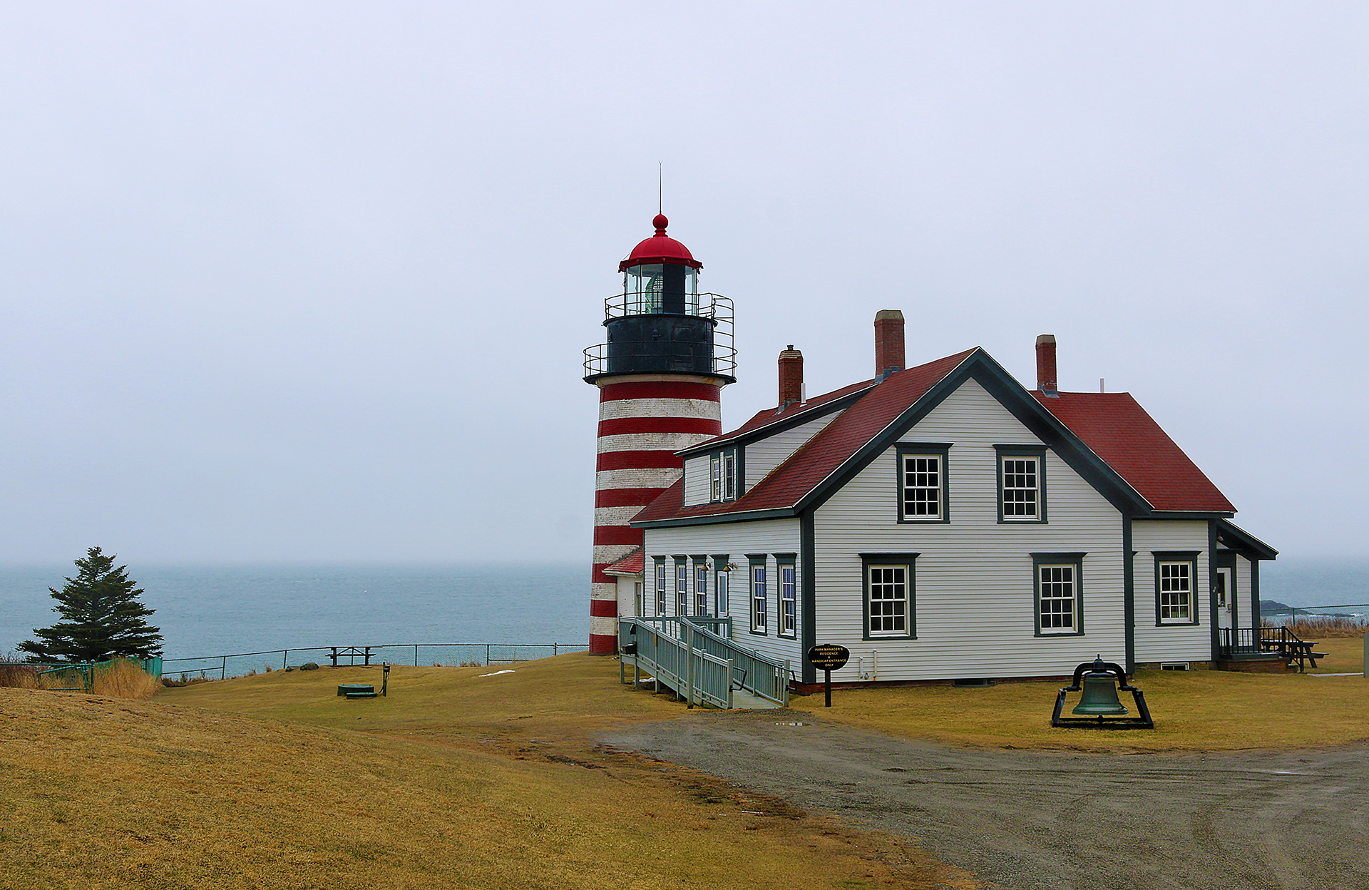 a lighthouse next to a body of water with West Quoddy Head Light in the background