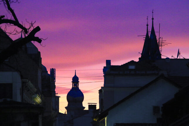 a silhouette of a building with a dome and a purple sky