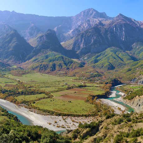 a river running through a valley with mountains in the background