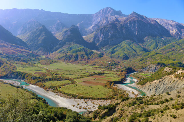 a river running through a valley with mountains in the background