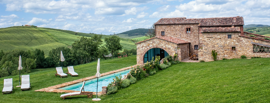 a pool in a grassy area with a stone building