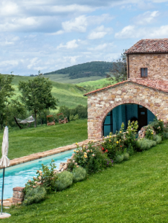a pool in a grassy area with a stone building