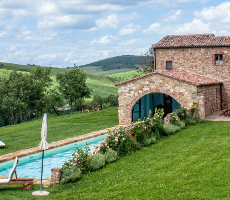 a pool in a grassy area with a stone building