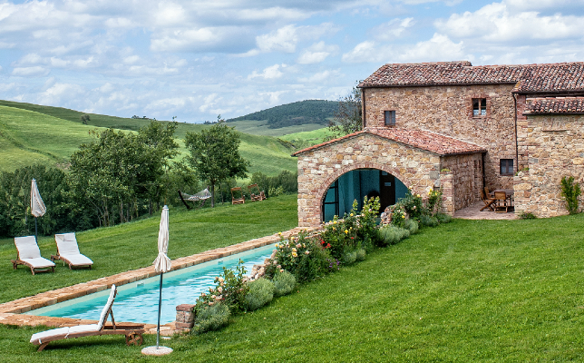 a pool in a grassy area with a stone building