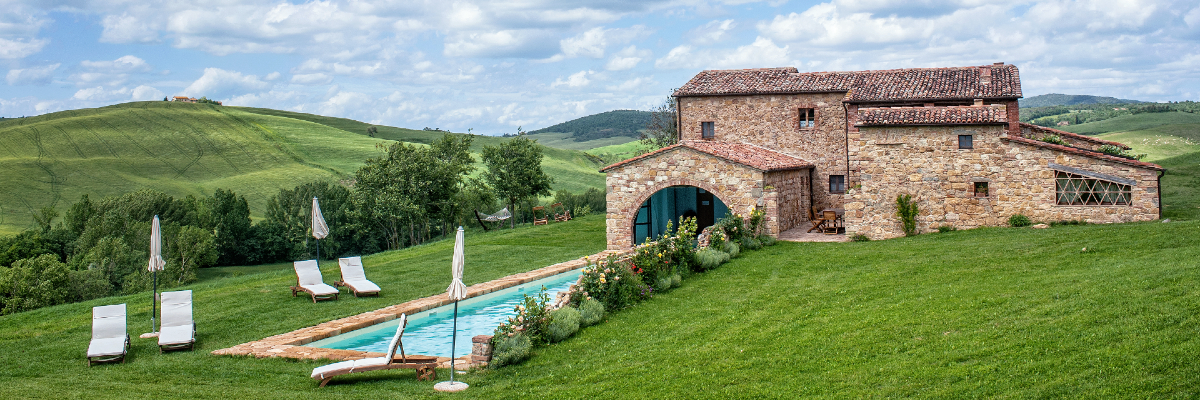 a pool in a grassy area with a stone building