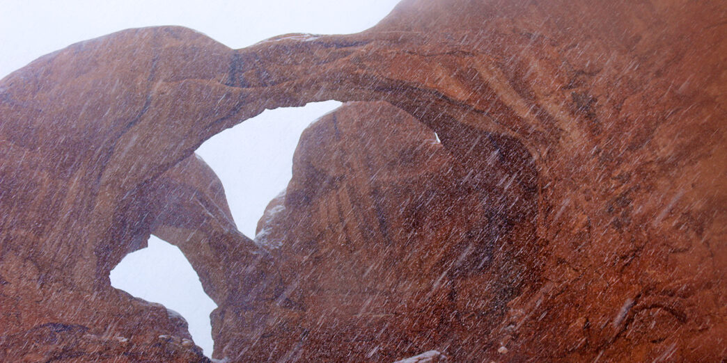 a rock formation with snow falling