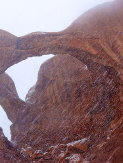 a rock formation with snow falling