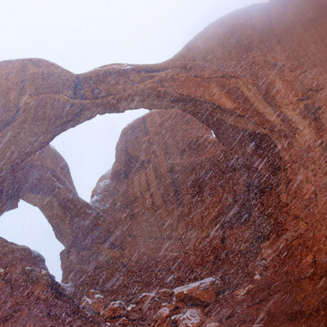 a rock formation with snow falling
