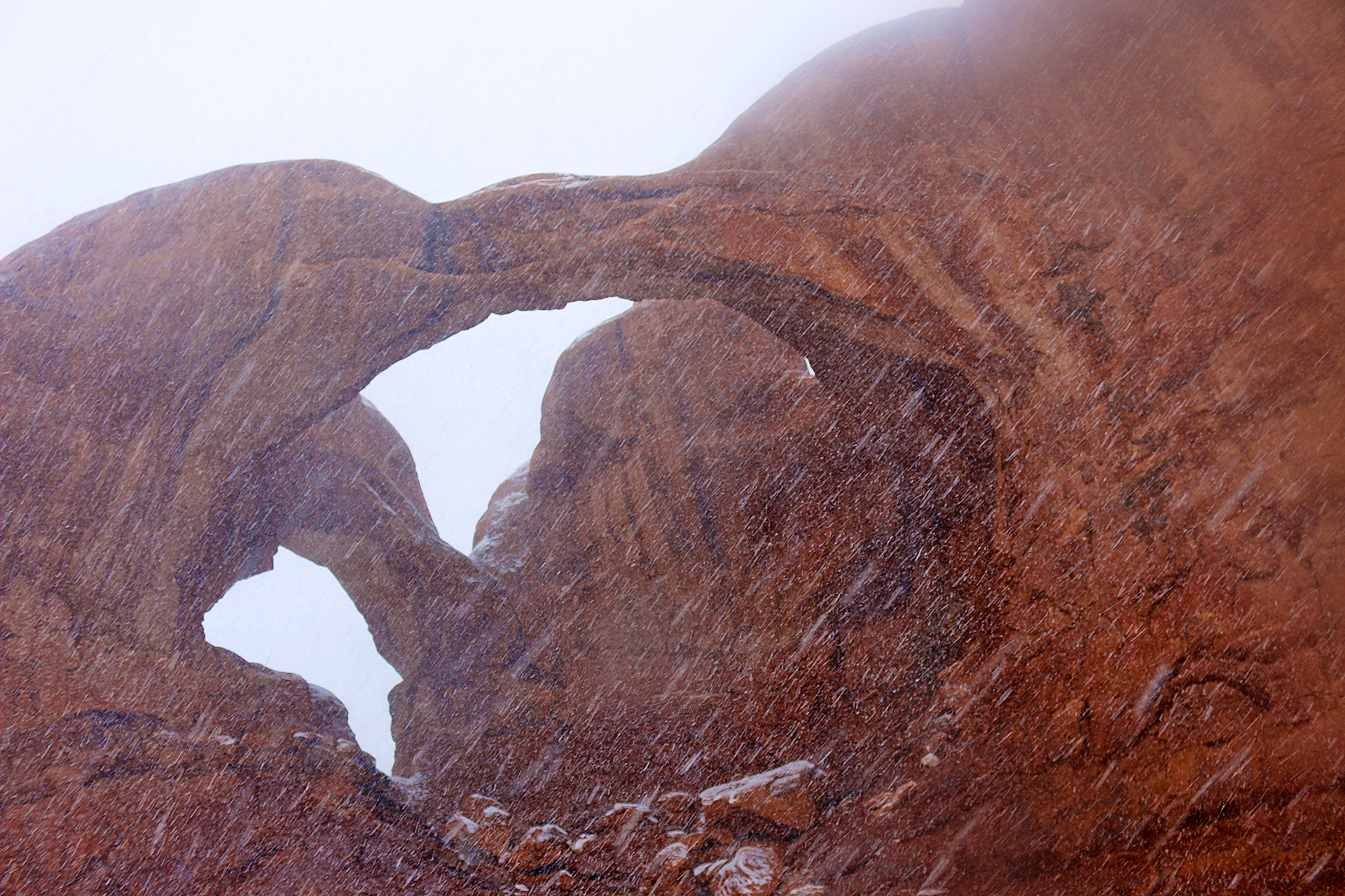 a rock formation with snow falling