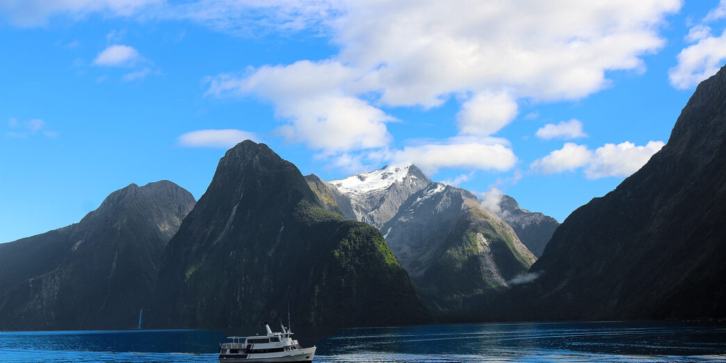 a boat in the water with mountains in the background with Milford Sound in the background