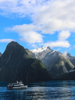 a boat in the water with mountains in the background with Milford Sound in the background