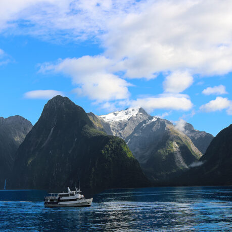a boat in the water with mountains in the background with Milford Sound in the background