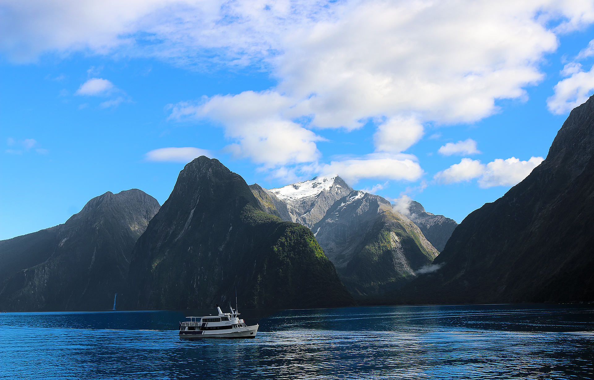 a boat in the water with mountains in the background with Milford Sound in the background