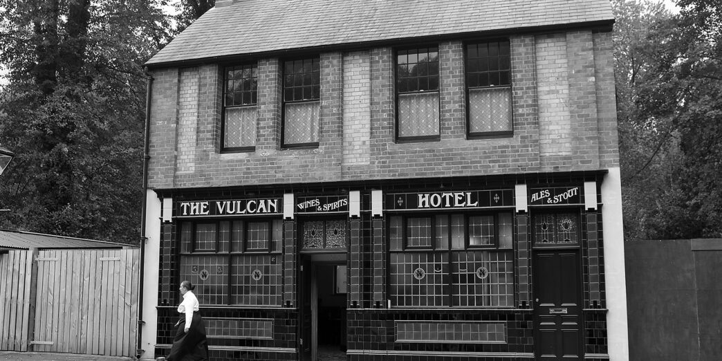 a person walking past a hotel with 251 Menlove Avenue in the background
