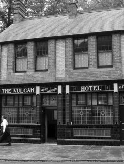 a person walking past a hotel with 251 Menlove Avenue in the background