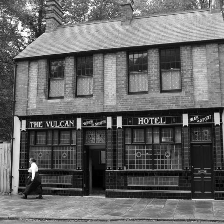 a person walking past a hotel with 251 Menlove Avenue in the background