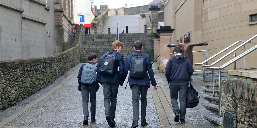 a group of boys walking down a path with backpacks