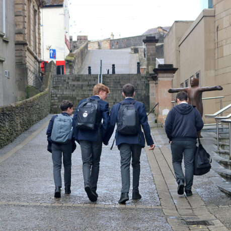 a group of boys walking down a path with backpacks