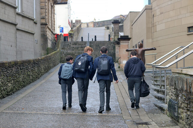 a group of boys walking down a path with backpacks