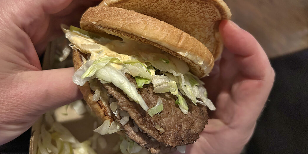 a person holding a burger