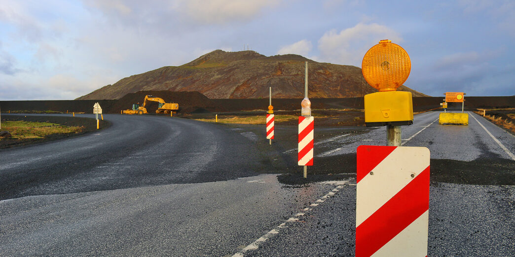 a road with a road sign and a hill in the background