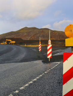 a road with a road sign and a hill in the background
