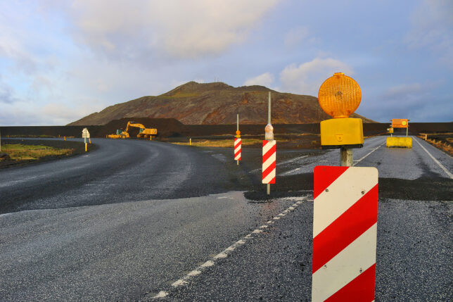 a road with a road sign and a hill in the background