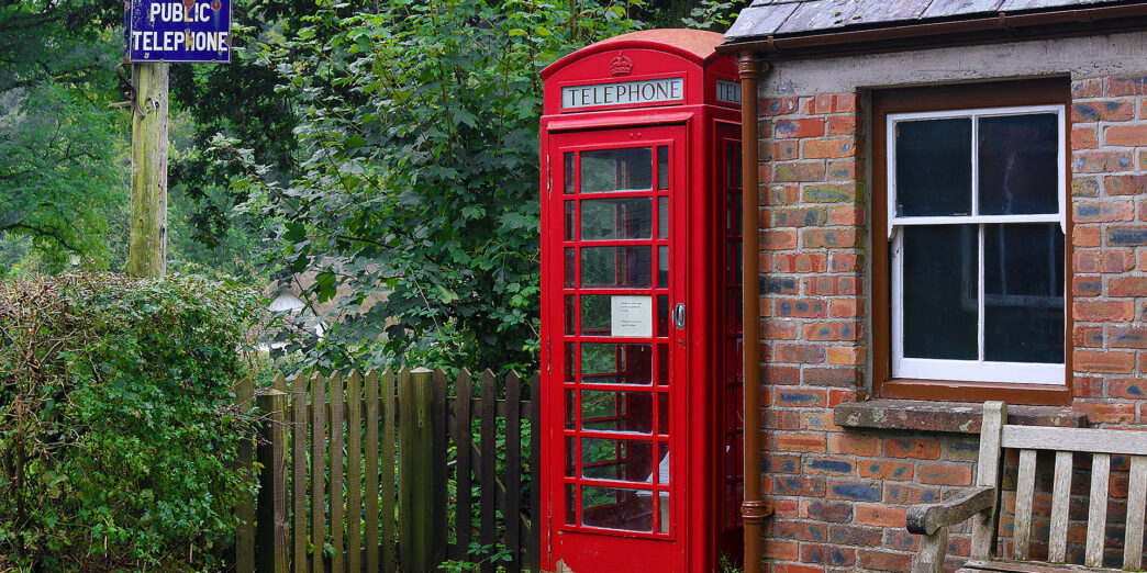 a red telephone booth next to a brick building