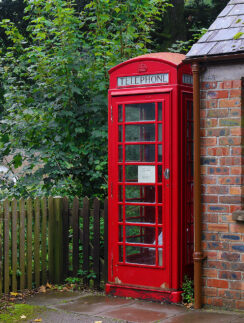 a red telephone booth next to a brick building
