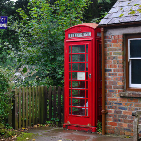 a red telephone booth next to a brick building