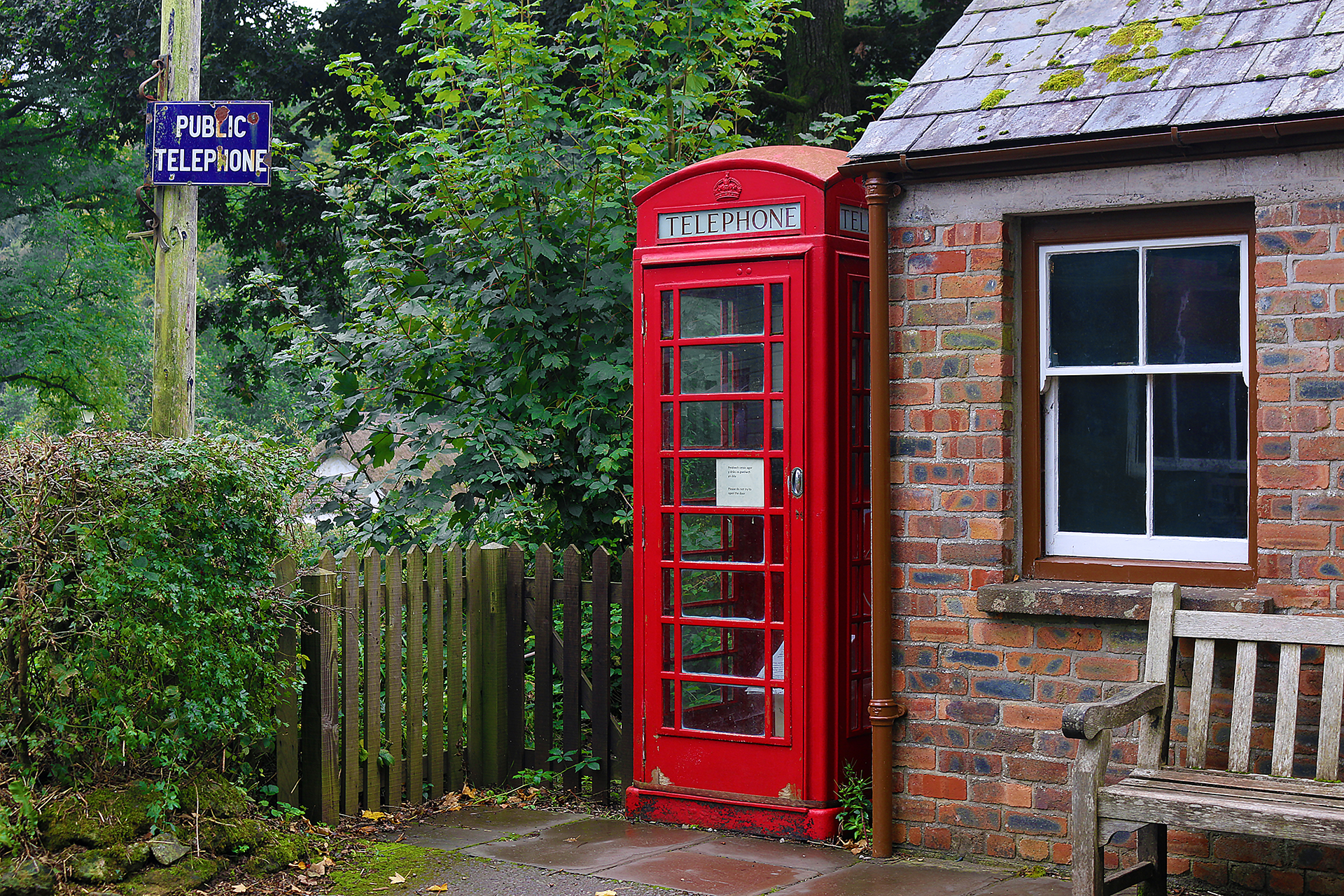 a red telephone booth next to a brick building