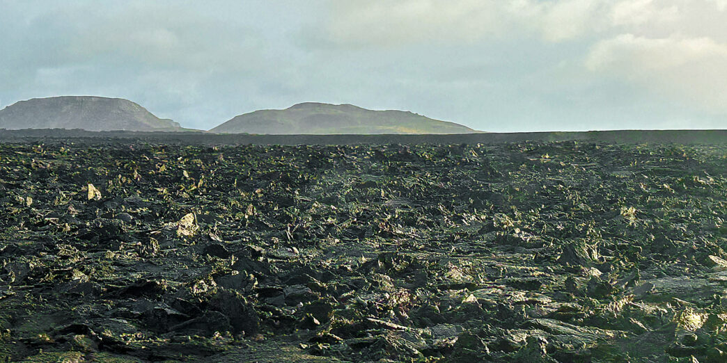 a large flat field with rocky hills in the background