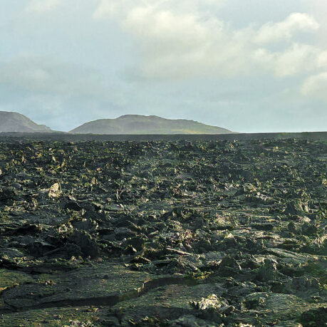 a large flat field with rocky hills in the background