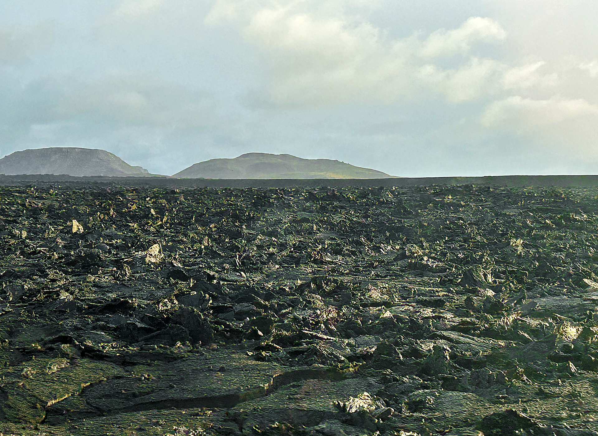 a large flat field with rocky hills in the background