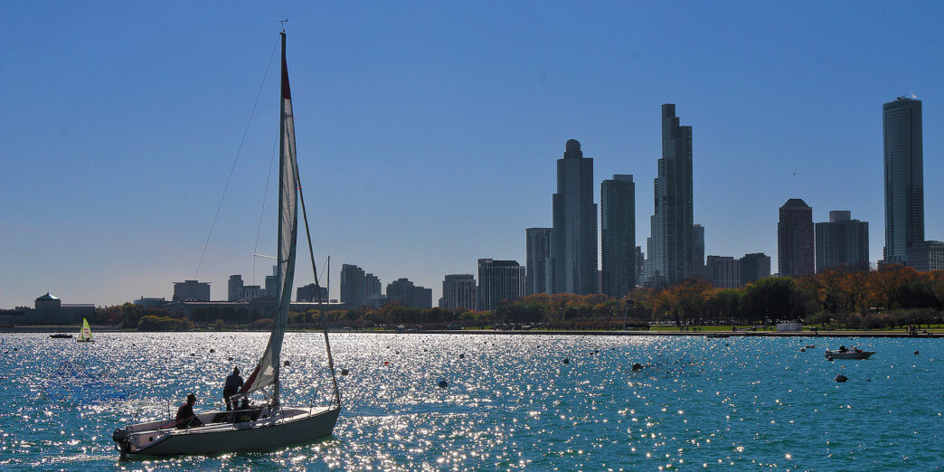 a sailboat on the water with a city in the background