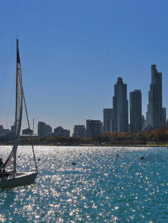a sailboat on the water with a city in the background